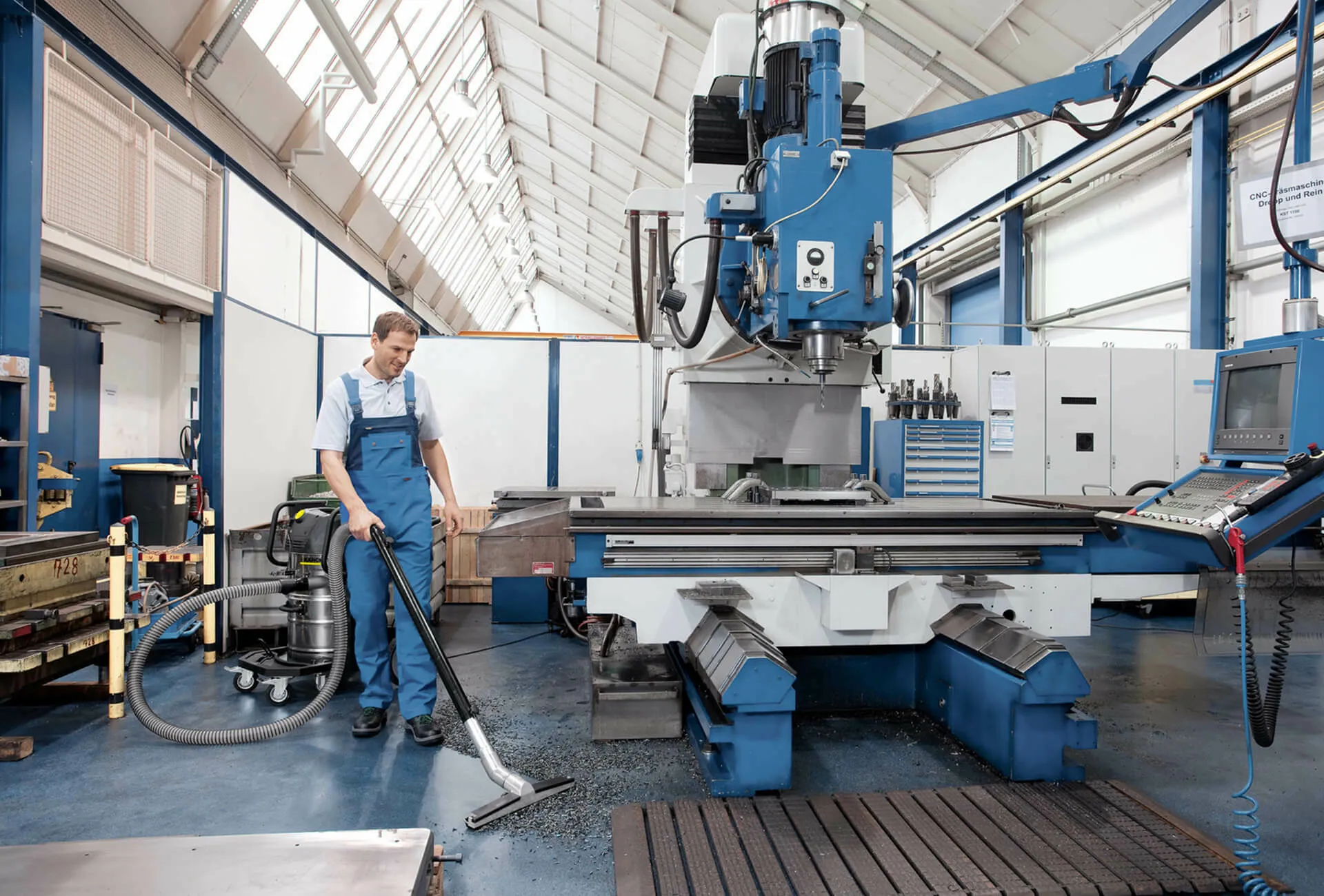 Person reinigt Boden in Industriehalle mit Kaercher Professional Industriesauger
