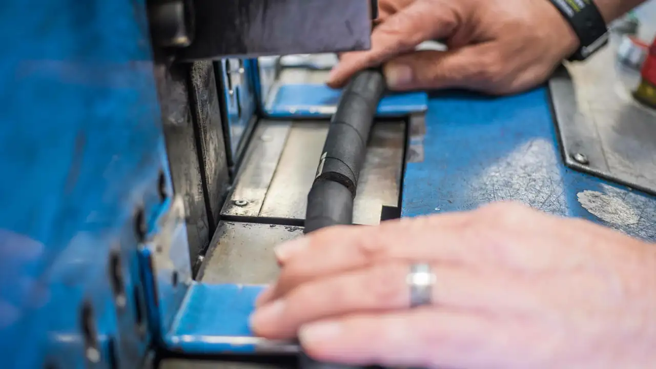 Nahaufnahme von zwei Händen, welche Schlauch schneidet